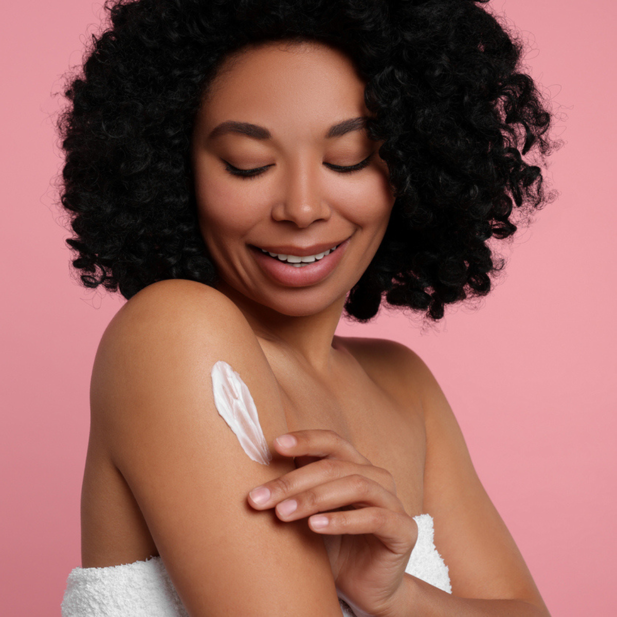 A black woman using body cream on her arm to smoot the skin texture and even her skin tone.